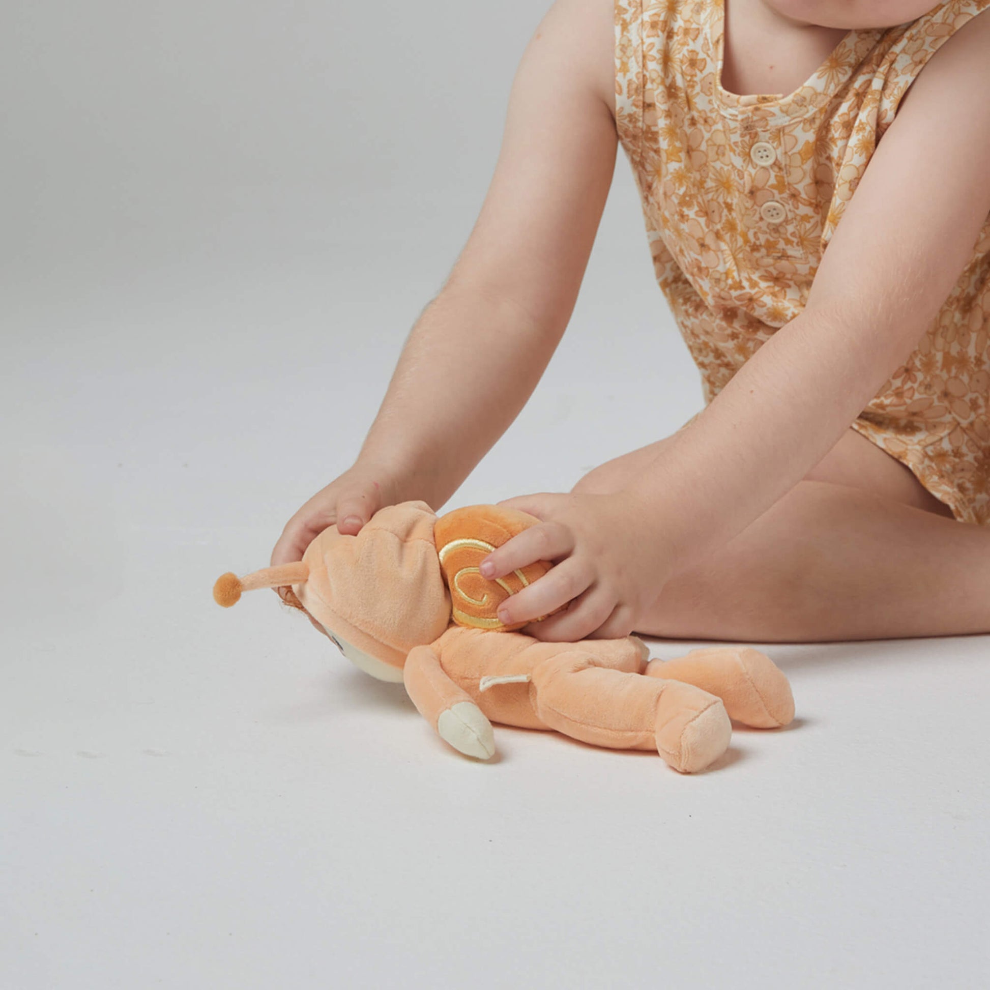 Child playing with a plush toy on a plain background