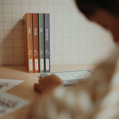 Four books on a table with a blurred person in the foreground