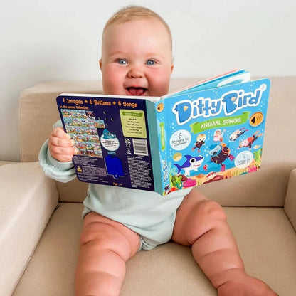 Baby sitting on a couch holding a colorful book titled 'Ditty Bird'.