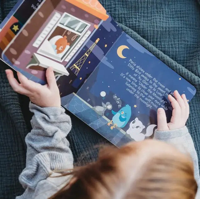 Child holding a colorful book with illustrations on a soft surface