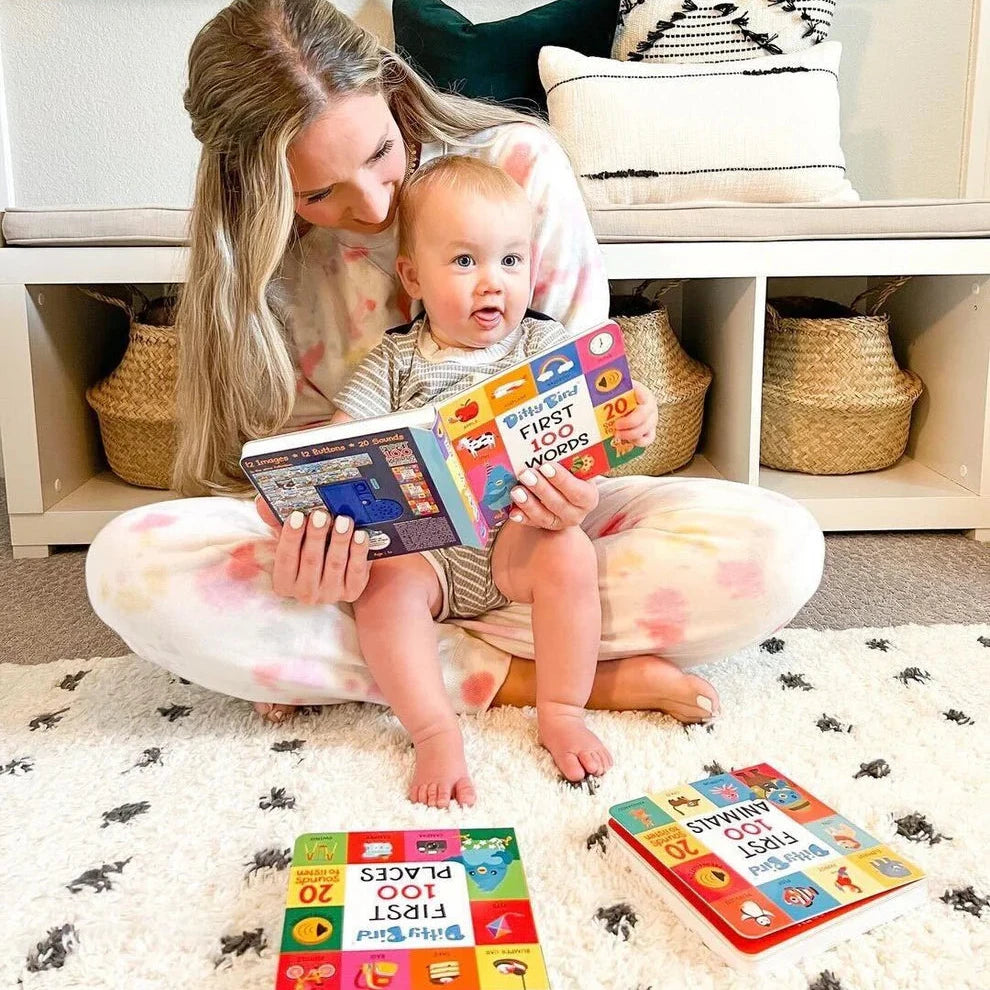 Woman reading a book to a baby in a home setting with books on shelves.
