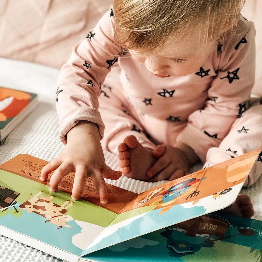 Child reading a book with a soft pink background
