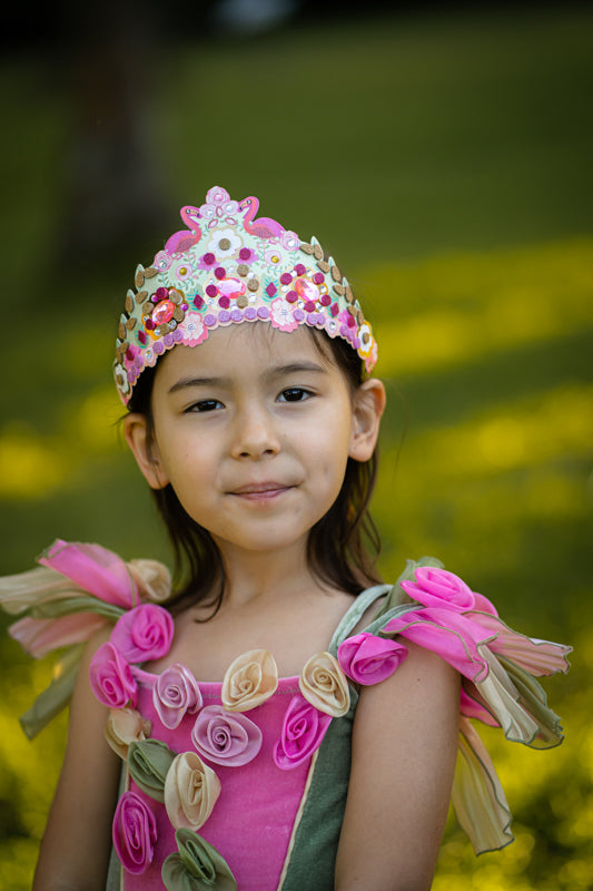 Young girl in a fairy costume with a tiara against a blurred green background