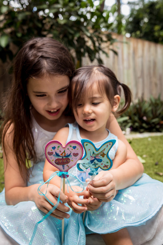 Children holding wands in a garden setting.