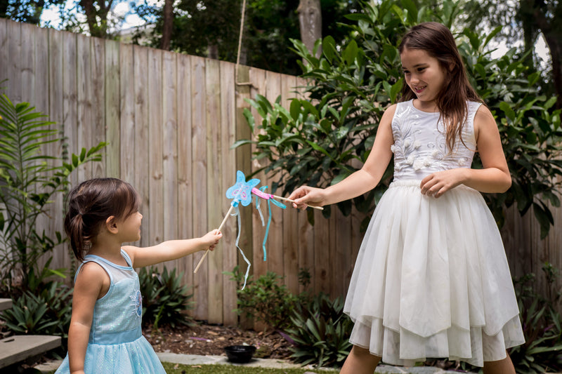 Children holding wands in a garden setting.