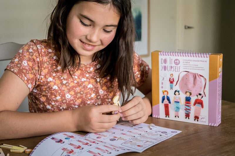 Child sitting at a table with Do It Yourself packaging and doll.