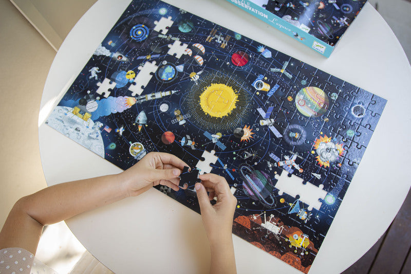 Solar system-themed puzzle on a table with hands working on it