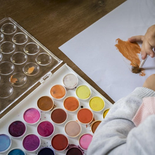Person painting with watercolors on a wooden table