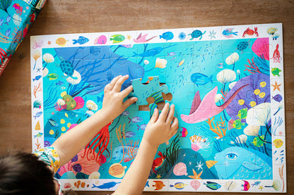 Child playing with an underwater-themed puzzle on a wooden table