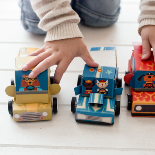 Children playing with colorful toy cars on a light wooden floor.