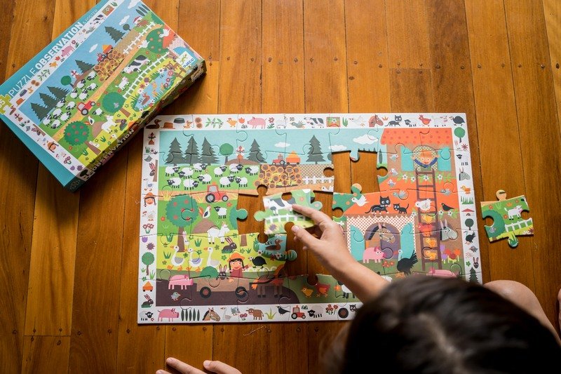 Child playing with a colorful puzzle on a wooden table