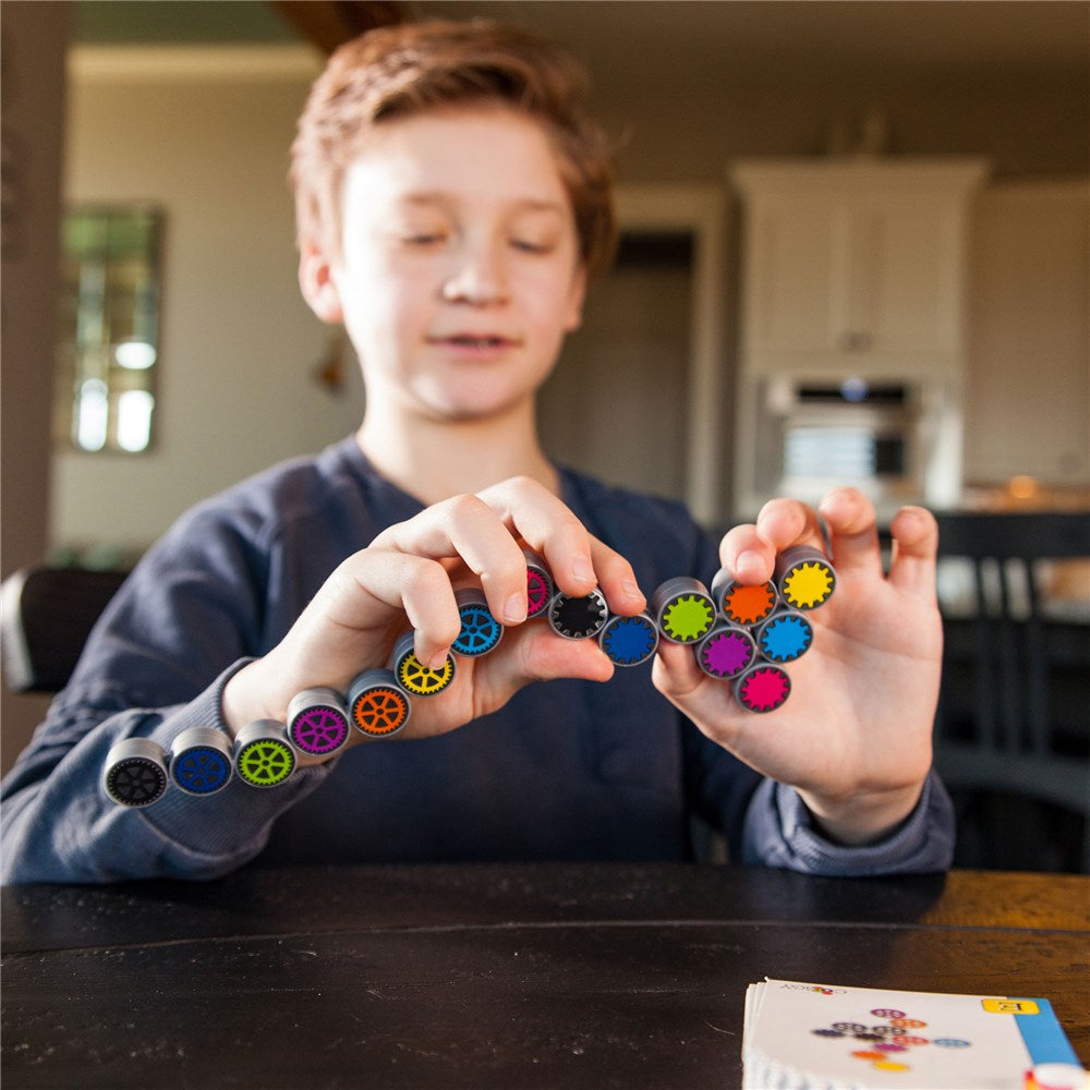Child holding colorful magnetic building toys in a kitchen setting