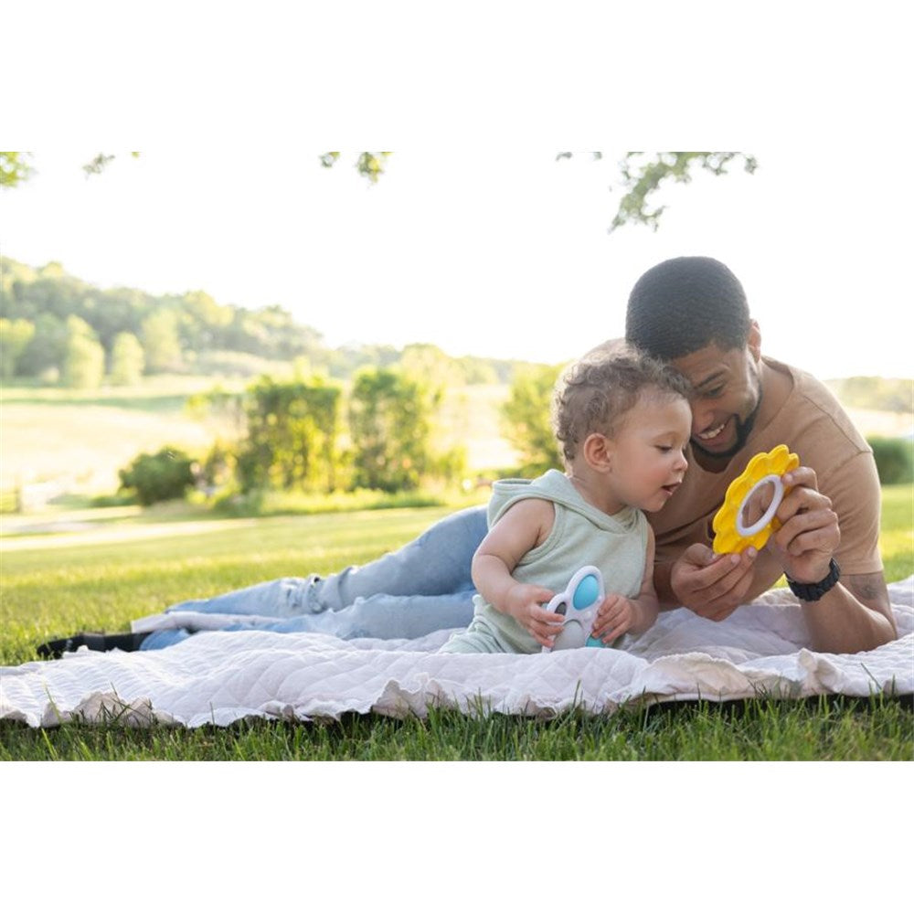 Man and child playing on a blanket in a park