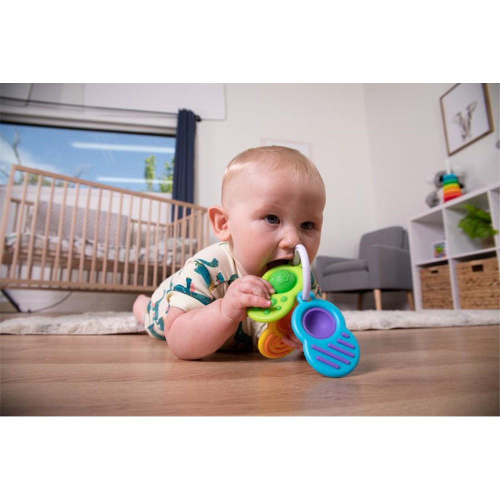 Baby playing with a colorful teething toy on a wooden floor.