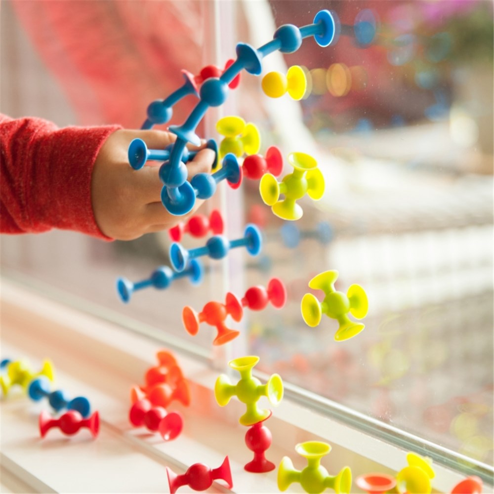 Colorful molecular model set with a child's hand interacting with it, blurred background