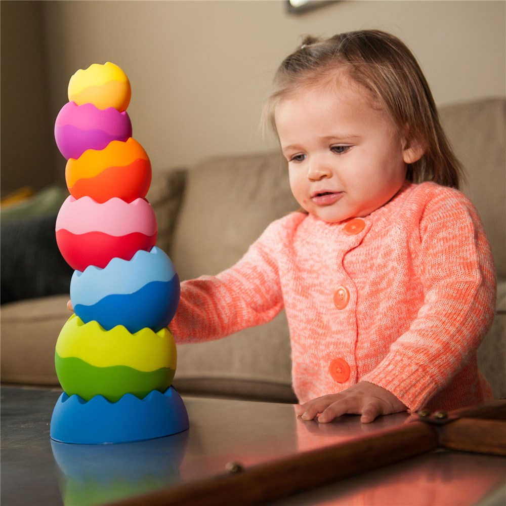 Child playing with a colorful stacking toy on a table.