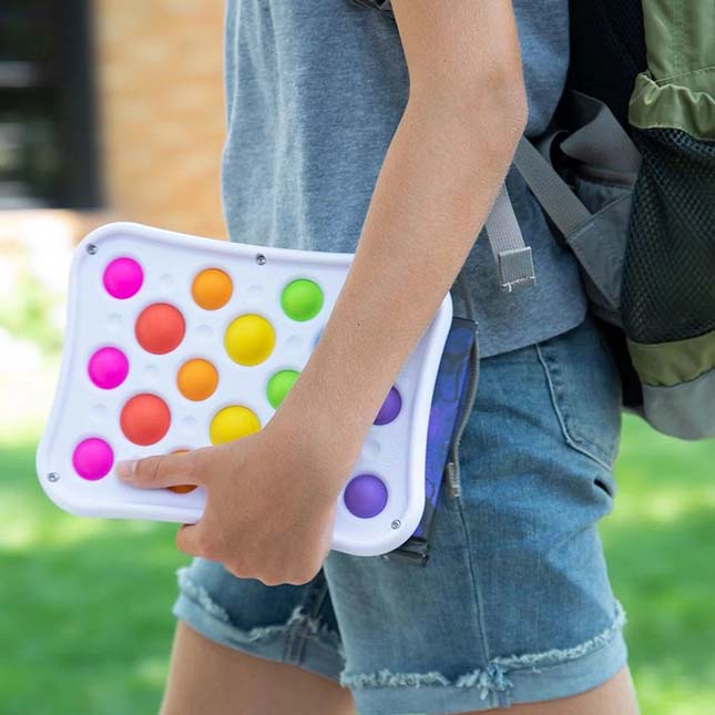 Person holding a colorful fidget toy with a blurred outdoor background