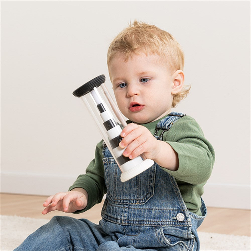 Child holding a transparent container with black lid and white base on a light background