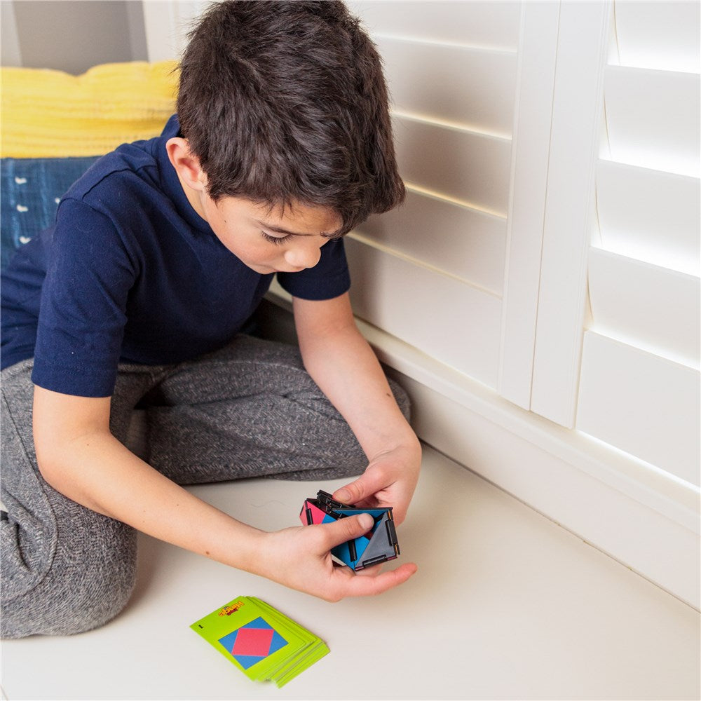 Child playing with geometric shapes on a light-colored floor.