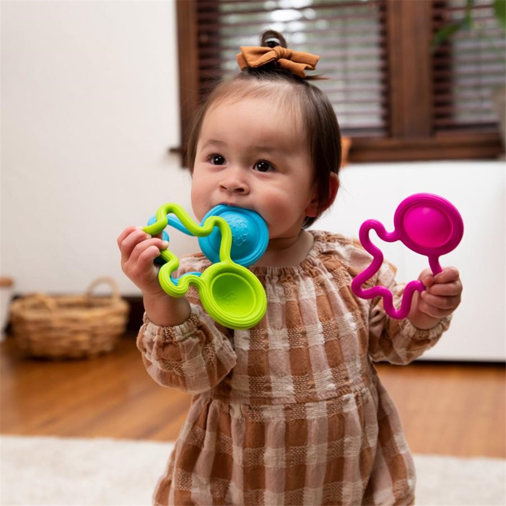 Child holding two colorful teething toys indoors