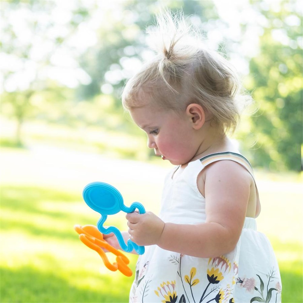Child holding colorful toys in a park setting