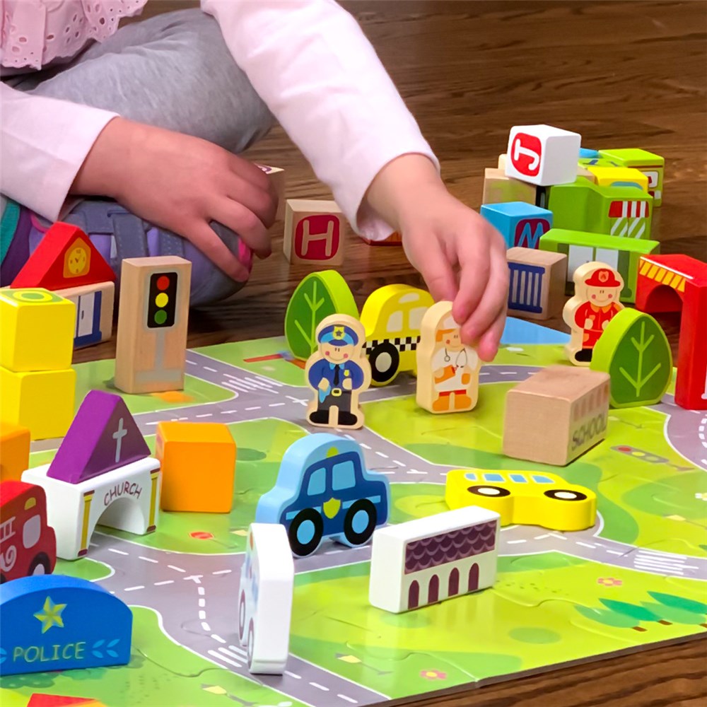 Children playing with a toy town set on a wooden table