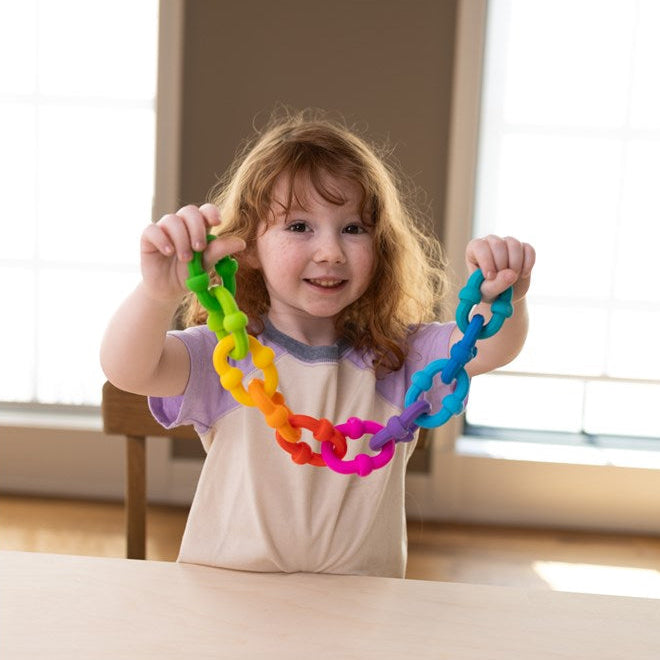 Child holding a colorful chain toy indoors