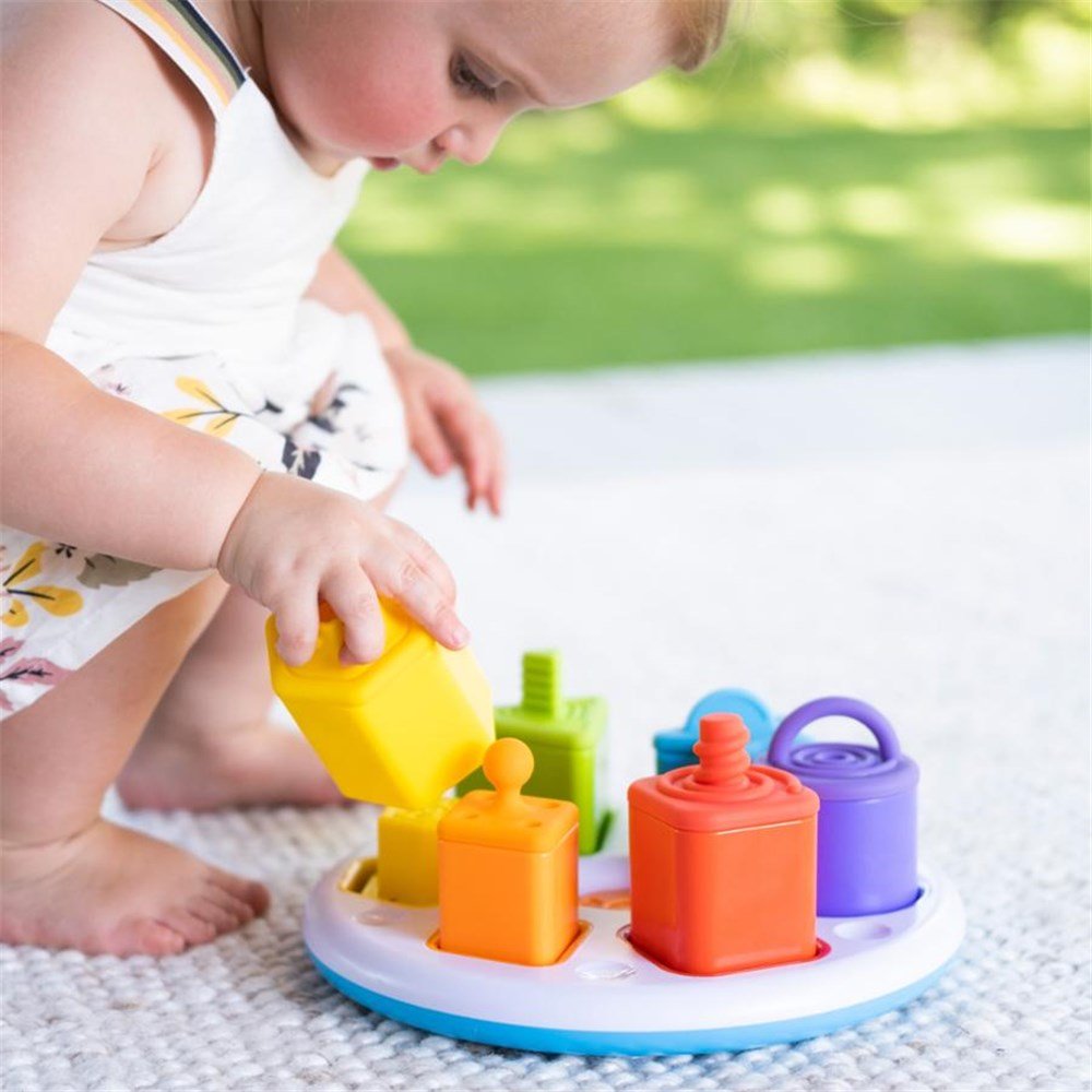 Child playing with colorful sand toys on a sandy surface outdoors.