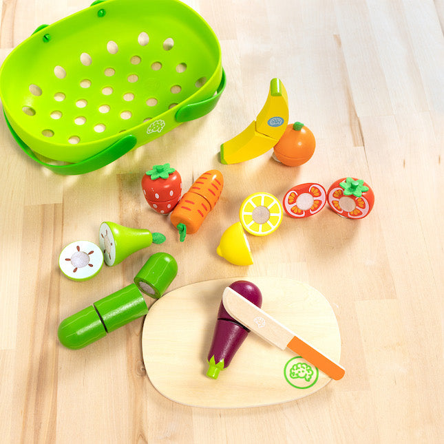 Colorful toy kitchen set with fruits, vegetables, and utensils on a wooden surface