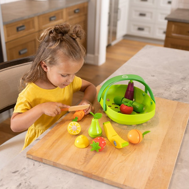 Child playing with toy vegetables on a cutting board in a kitchen
