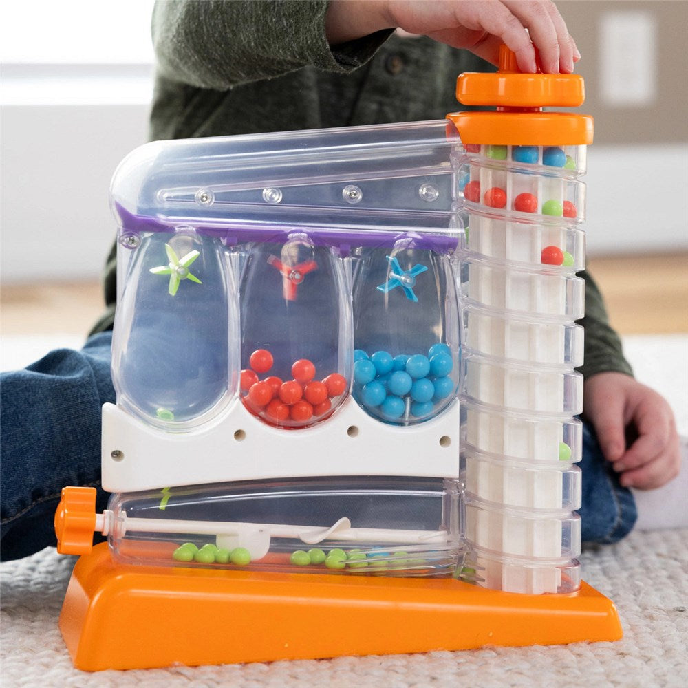 Children's educational toy with colorful beads and compartments on a carpeted floor.