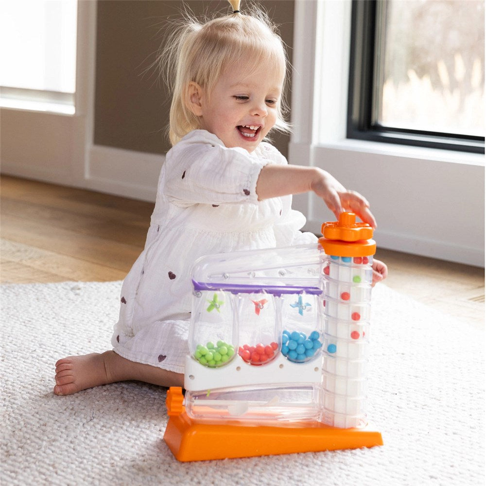 Child playing with a colorful educational toy on a carpeted floor.