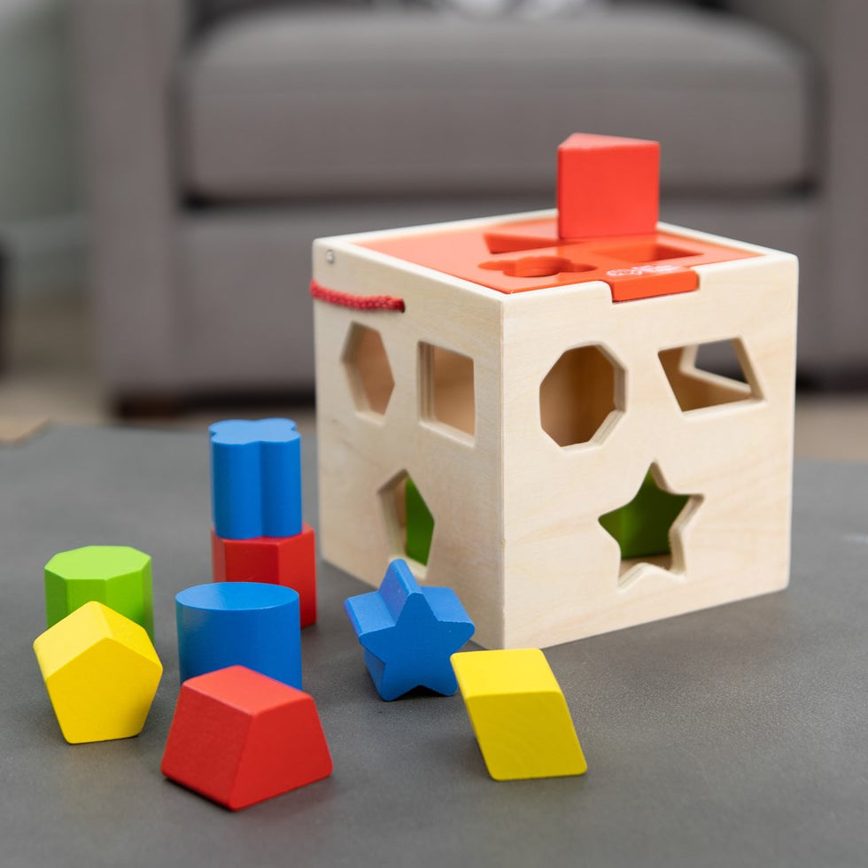 Wooden shape sorting cube with colorful blocks on a gray surface