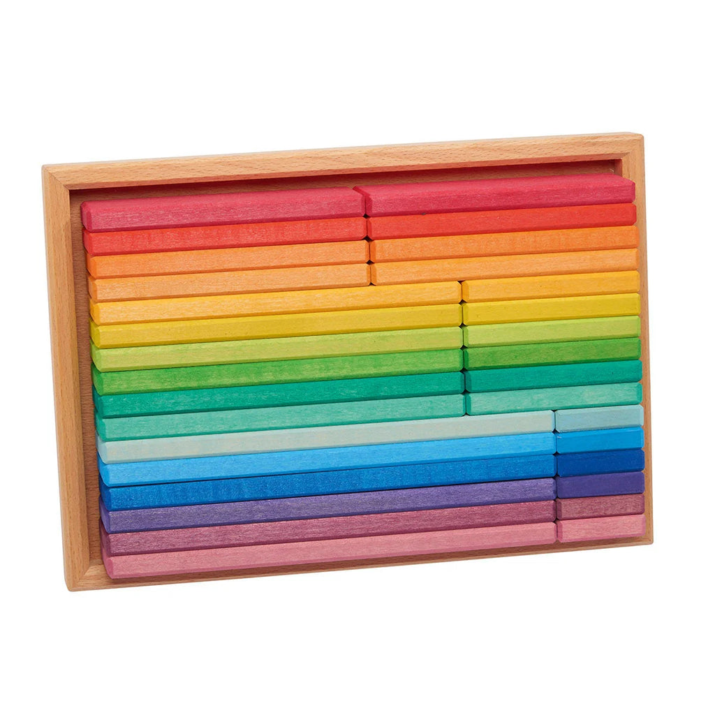 Rainbow wooden blocks arranged in a light natural wood tray on a plain white background.