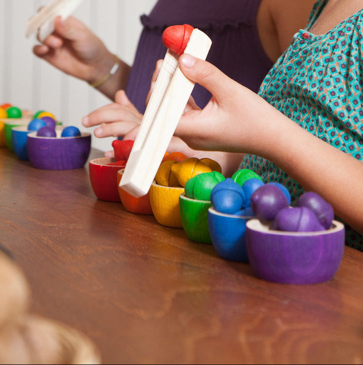 Two young girls playing with colorful toys at a table.