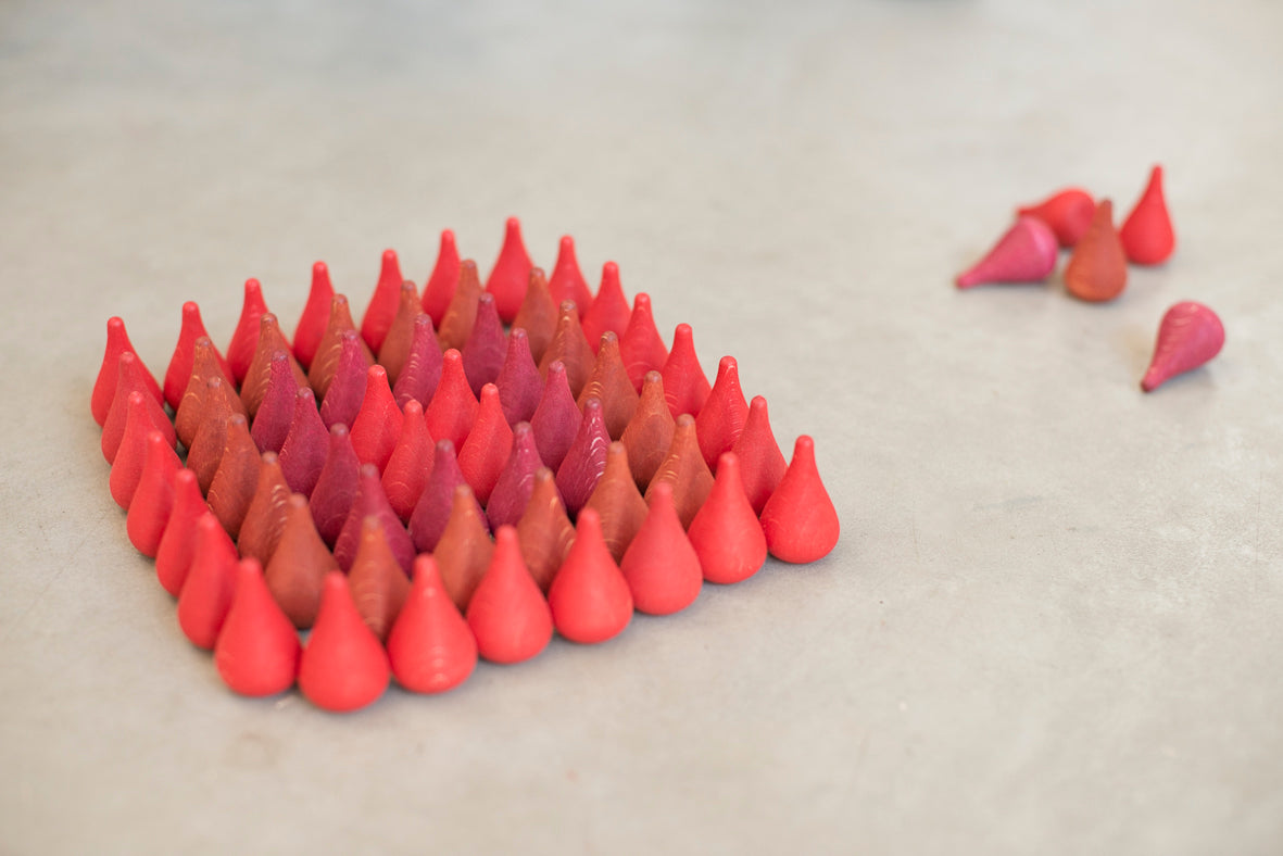 Red and pink cone-shaped objects arranged in a pattern on a light gray surface.