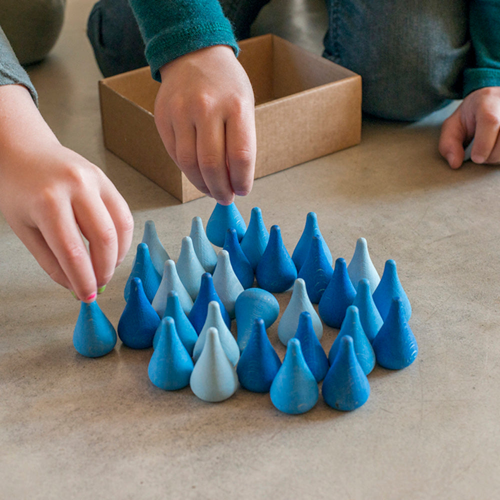 Children playing with blue and white ceramic teapots on a beige surface