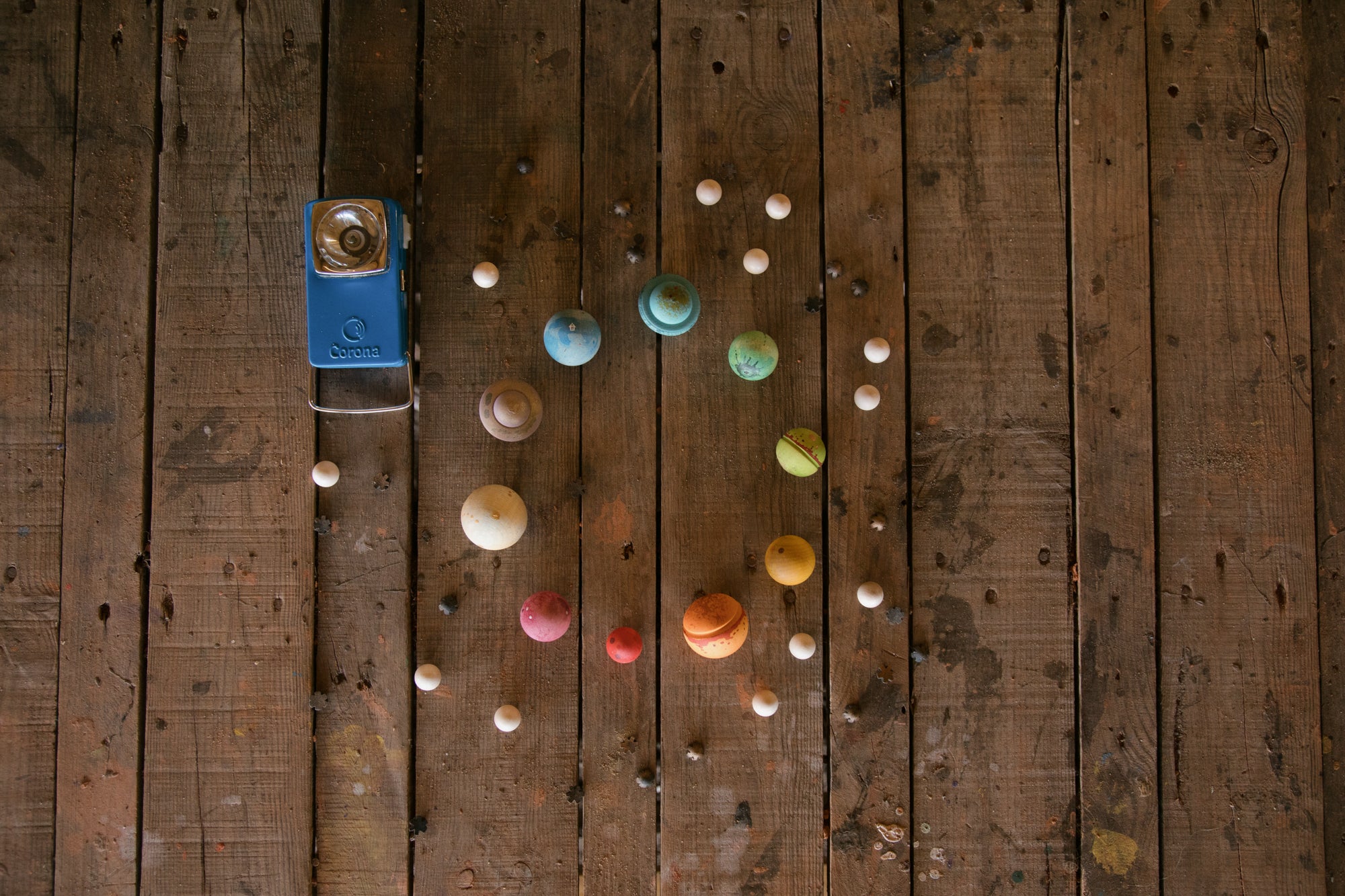 Colorful bottle caps on a wooden surface with a blue bottle cap and small container.