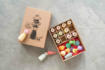 Colorful toy nins  in an open box with a cardboard box featuring illustrations on a gray surface.