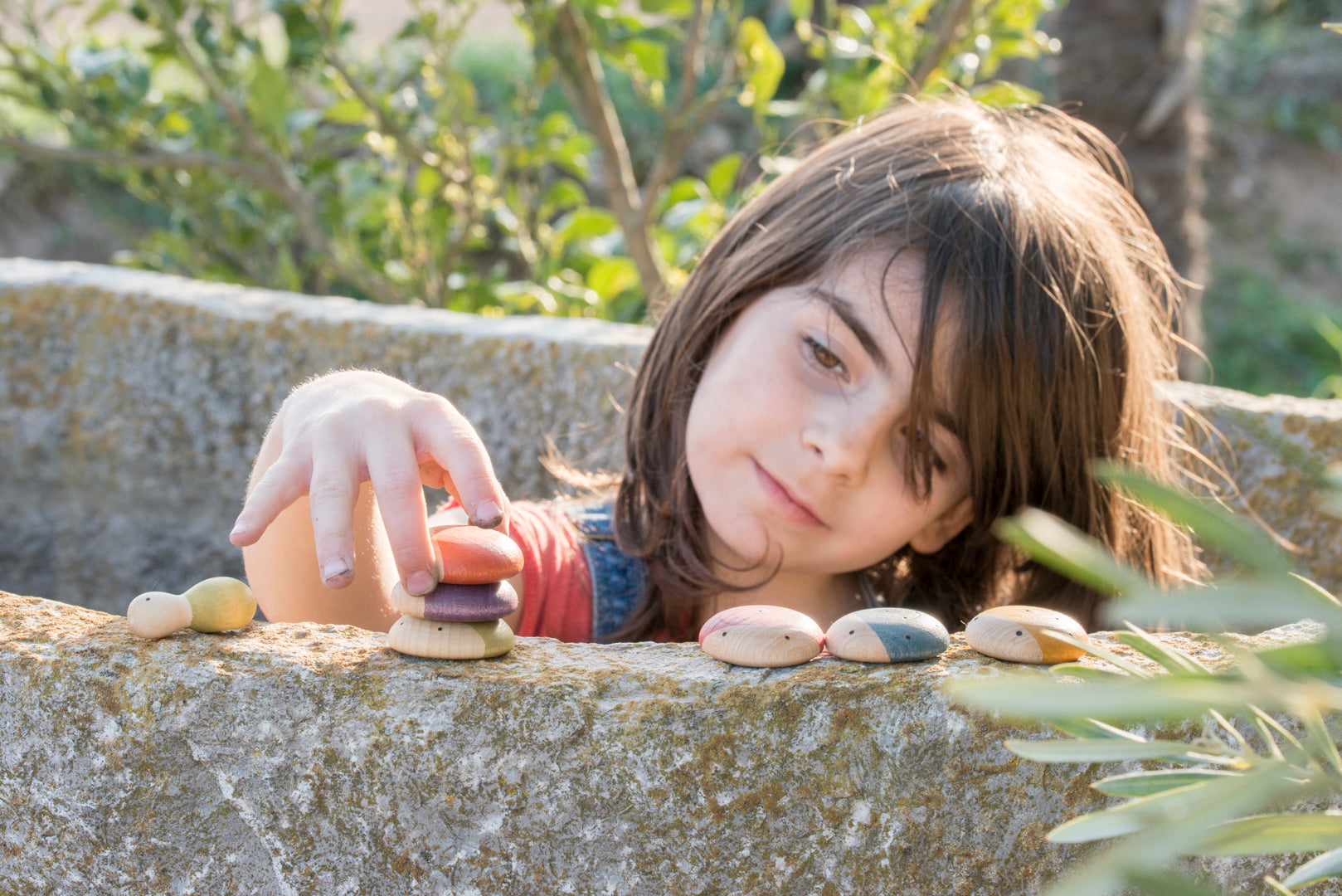 Child playing outdoors with wooden insects