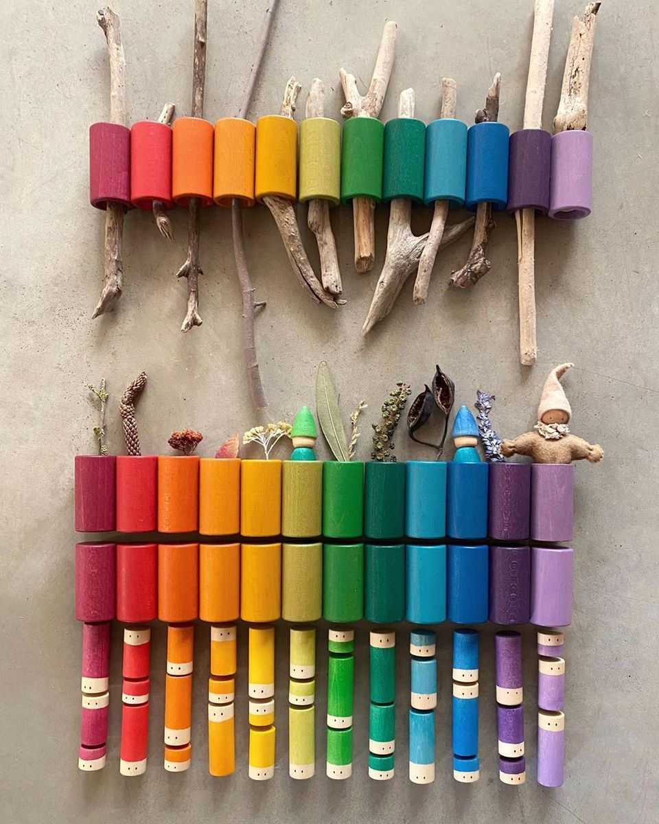 Colorful wooden toy xylophone made from sticks and crayon holders on a gray wall.