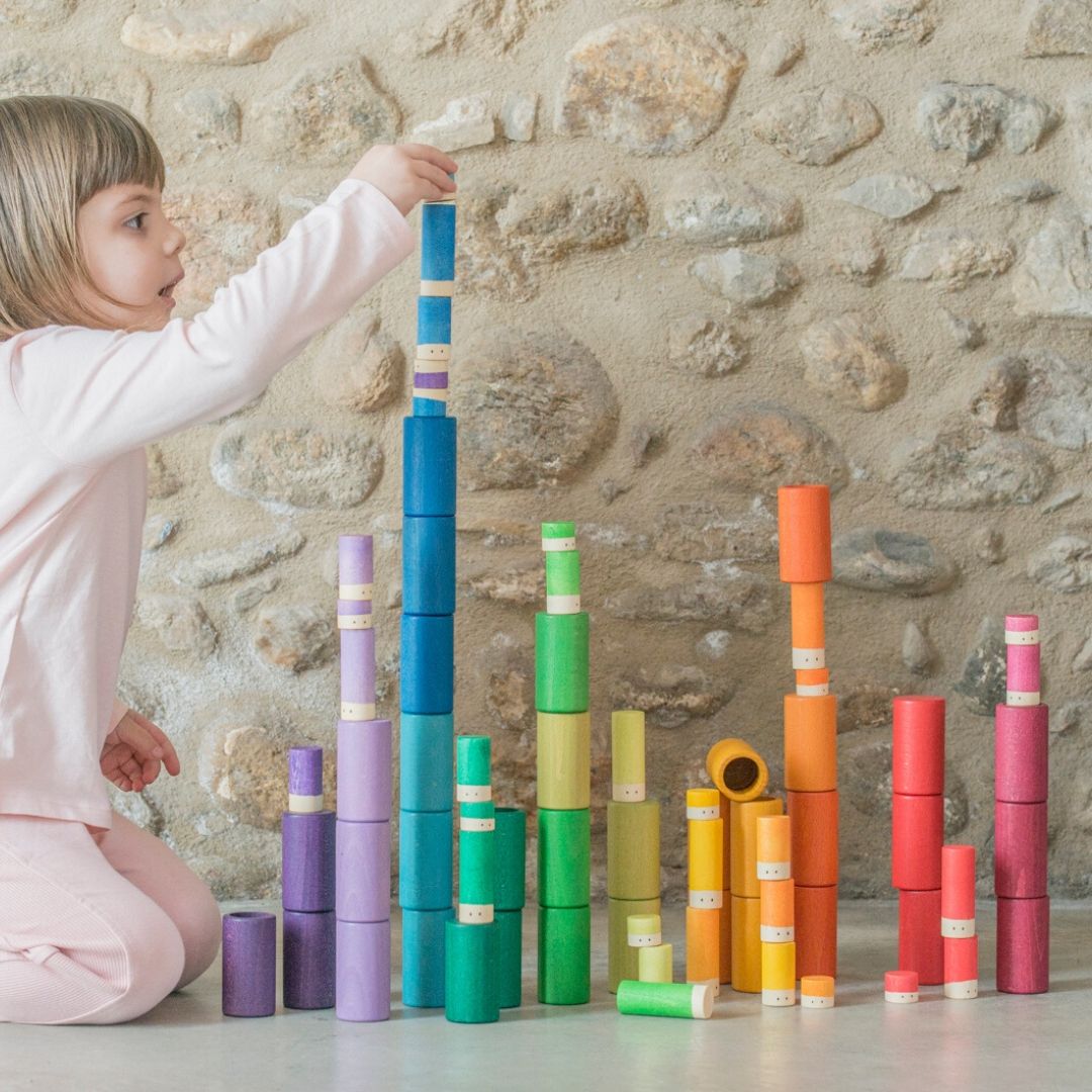 Child playing with colorful building blocks against a stone wall.