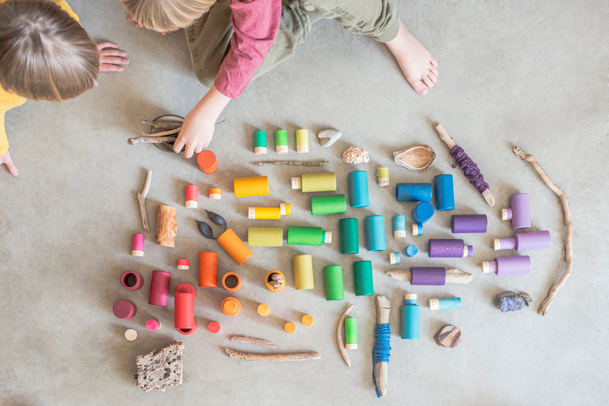 Children playing with colorful wooden toys on a concrete floor