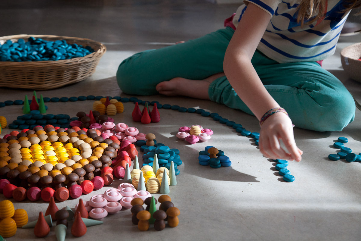Person sitting on the floor surrounded by colorful clay sculptures and a woven basket.