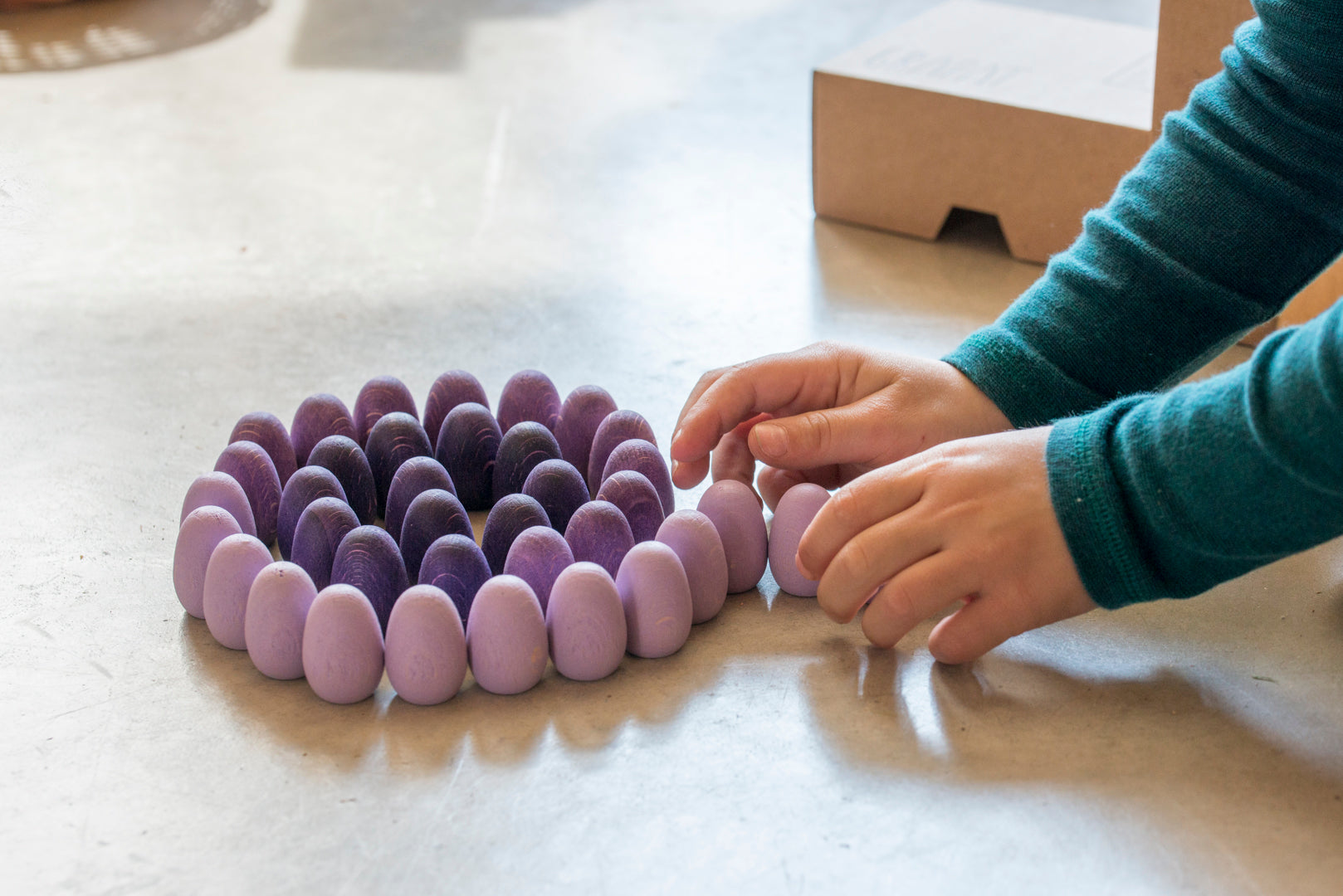 Person arranging purple eggs on a light surface