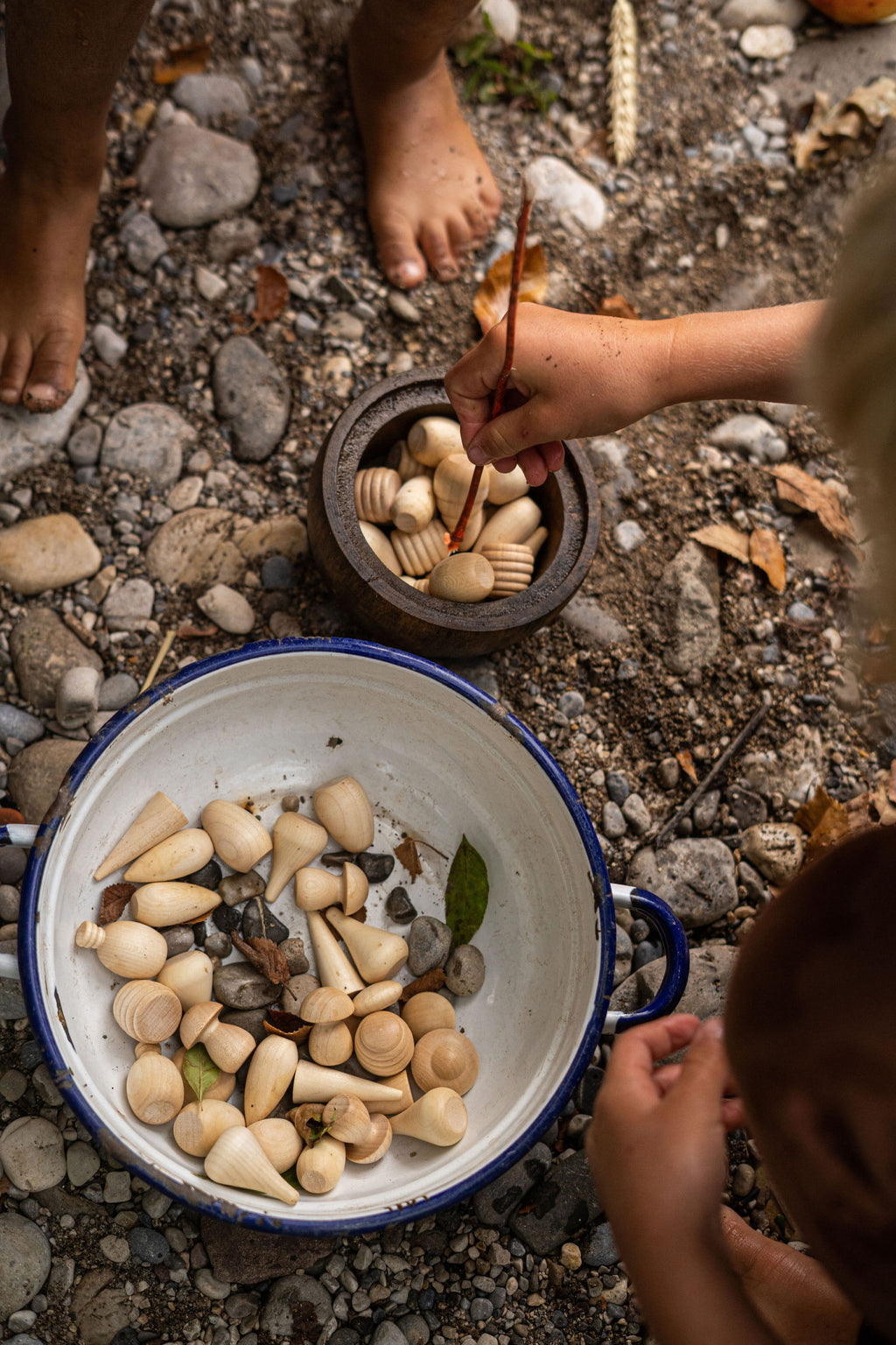 Children playing with stones and a pot on a rocky ground