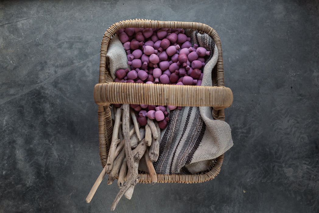 Wicker basket with purple beads and striped fabric on a dark gray background