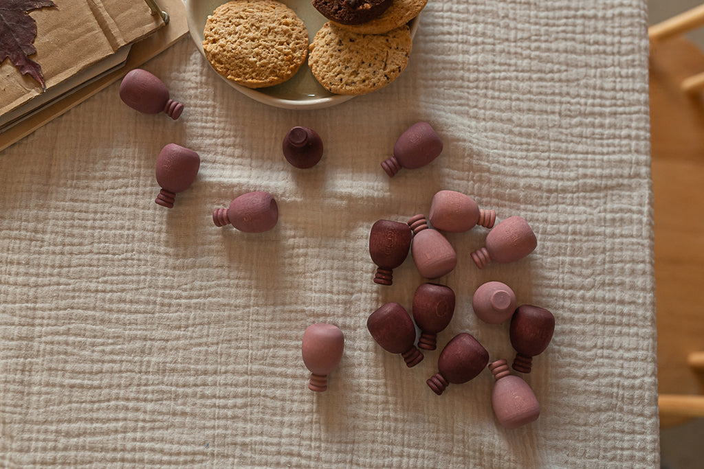 Purple wooden pineapples on a textured fabric surface with cookies in the background.