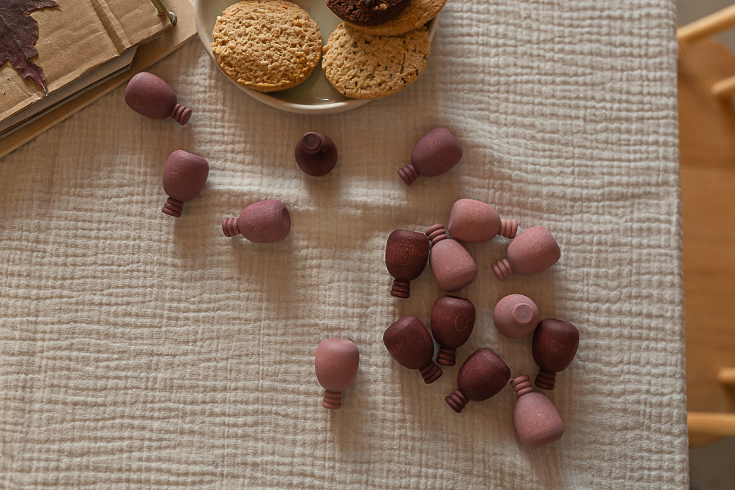 Purple wooden pineapples on a textured fabric surface with cookies in the background.