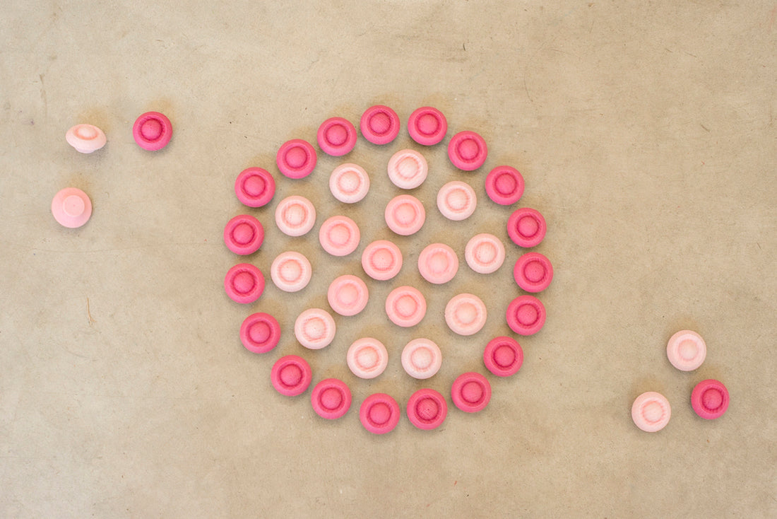 Pink circular objects arranged in a spiral pattern on a beige background